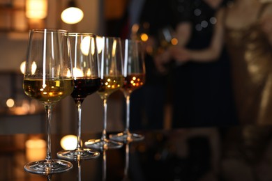 Photo of Different tasty wines in glasses on table indoors, selective focus
