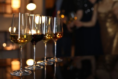 Different tasty wines in glasses on table indoors, selective focus