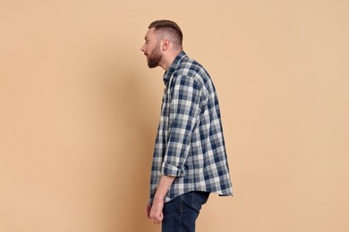 Man with poor posture on pale orange background