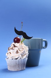 Photo of Happy Father's Day. Cupcake with mustache topper and cup on blue background