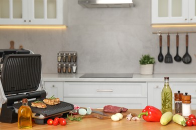 Photo of Electric grill and different products on wooden table