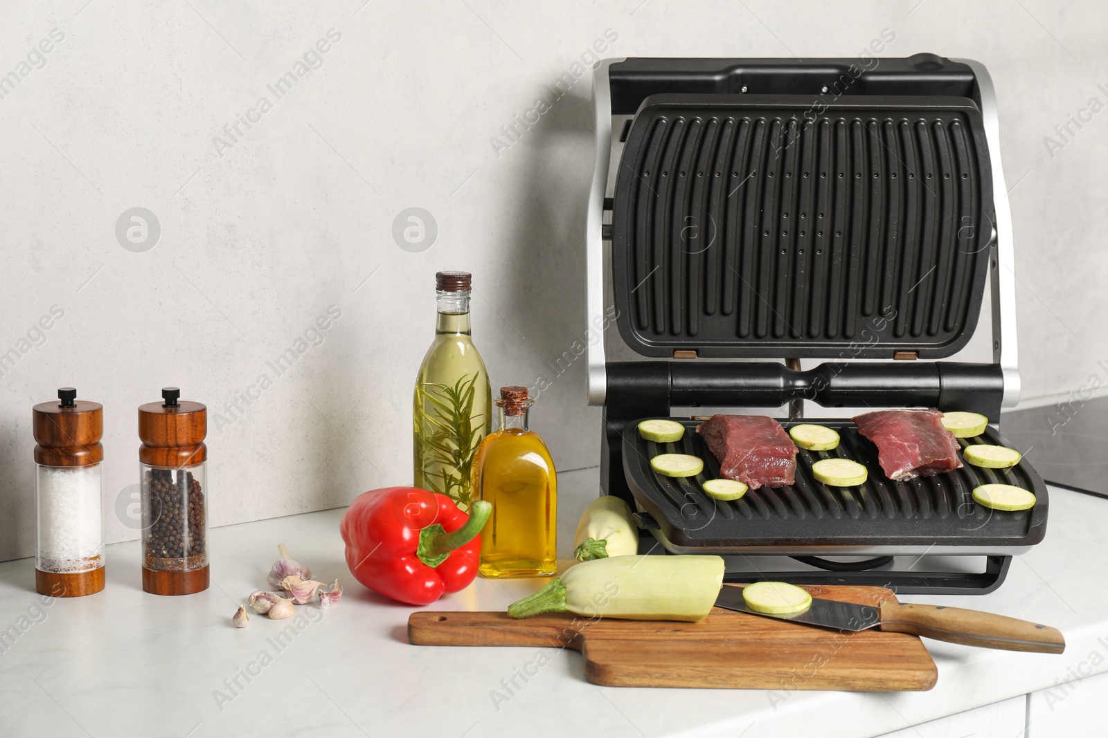 Photo of Electric grill and different products on white wooden table
