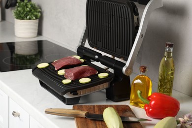 Photo of Electric grill and different products on white wooden table