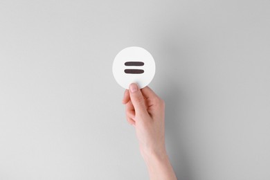 Photo of Woman holding equals sign on light background, closeup