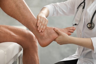 Photo of Sports injury. Doctor examining patient's foot in hospital, closeup