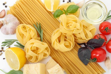 Different types of pasta and ingredients on white background, flat lay