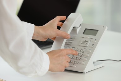 Assistant taking telephone handset at white table, closeup