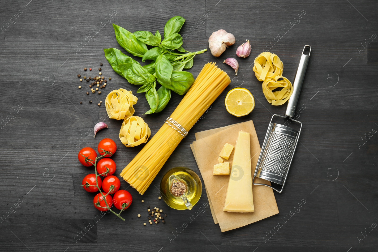 Photo of Different types of pasta, products, peppercorns and garter on dark wooden table, flat lay