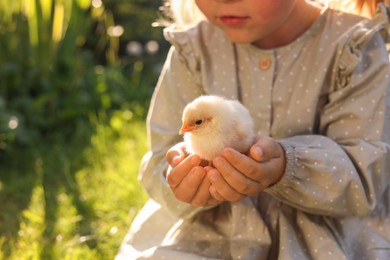 Photo of Little girl with cute chick outdoors, closeup. Baby animal