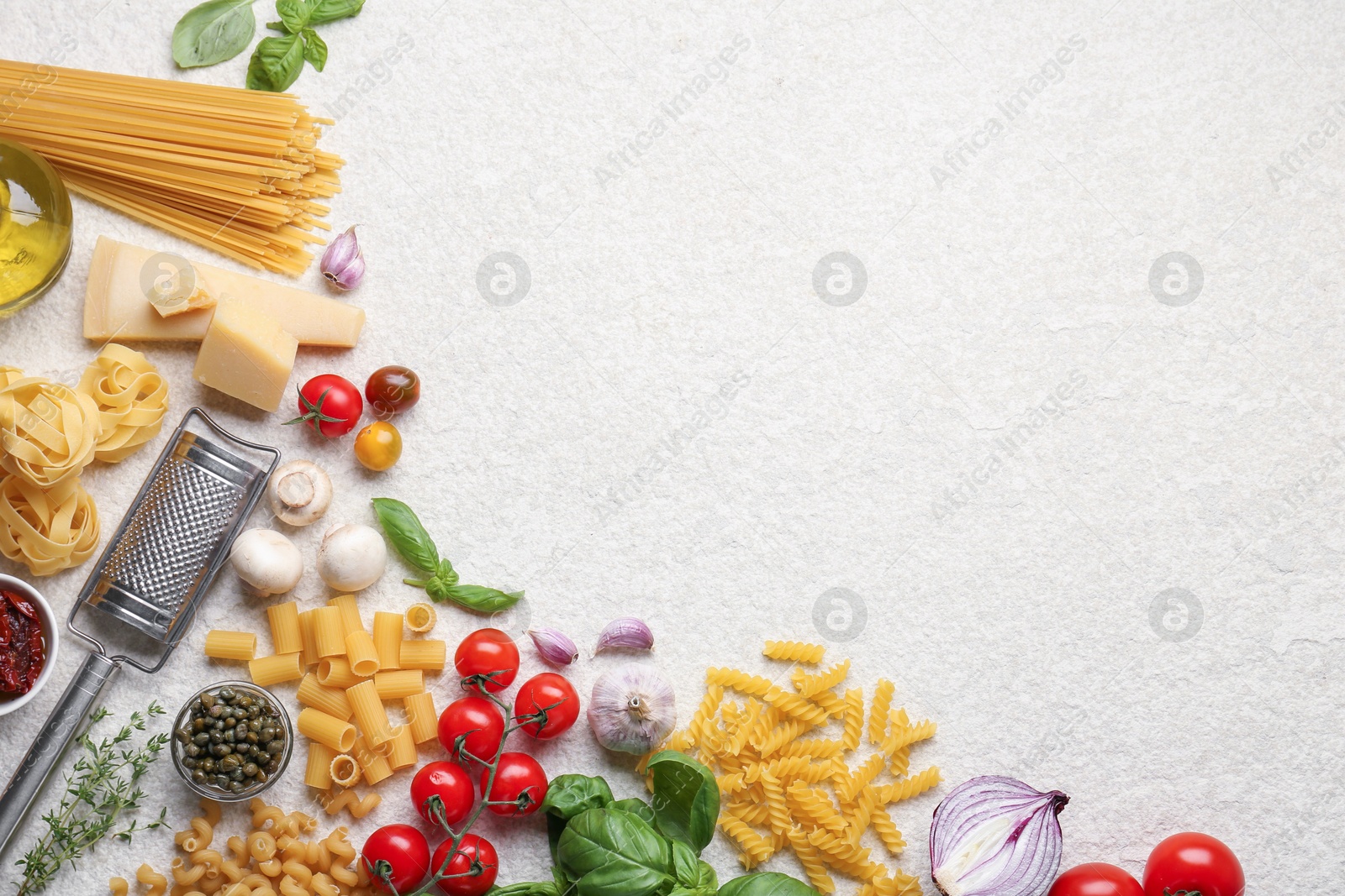 Photo of Different types of pasta, grater, spices and products on light table, flat lay. Space for text