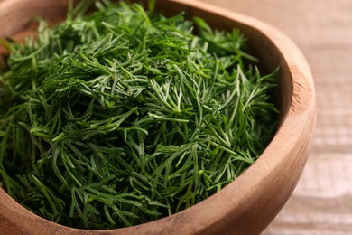 Photo of Fresh cut dill in wooden bowl on table, closeup