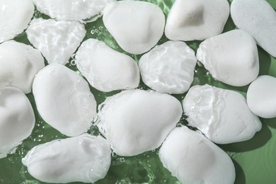 Photo of Spa stones in water on light green background, flat lay