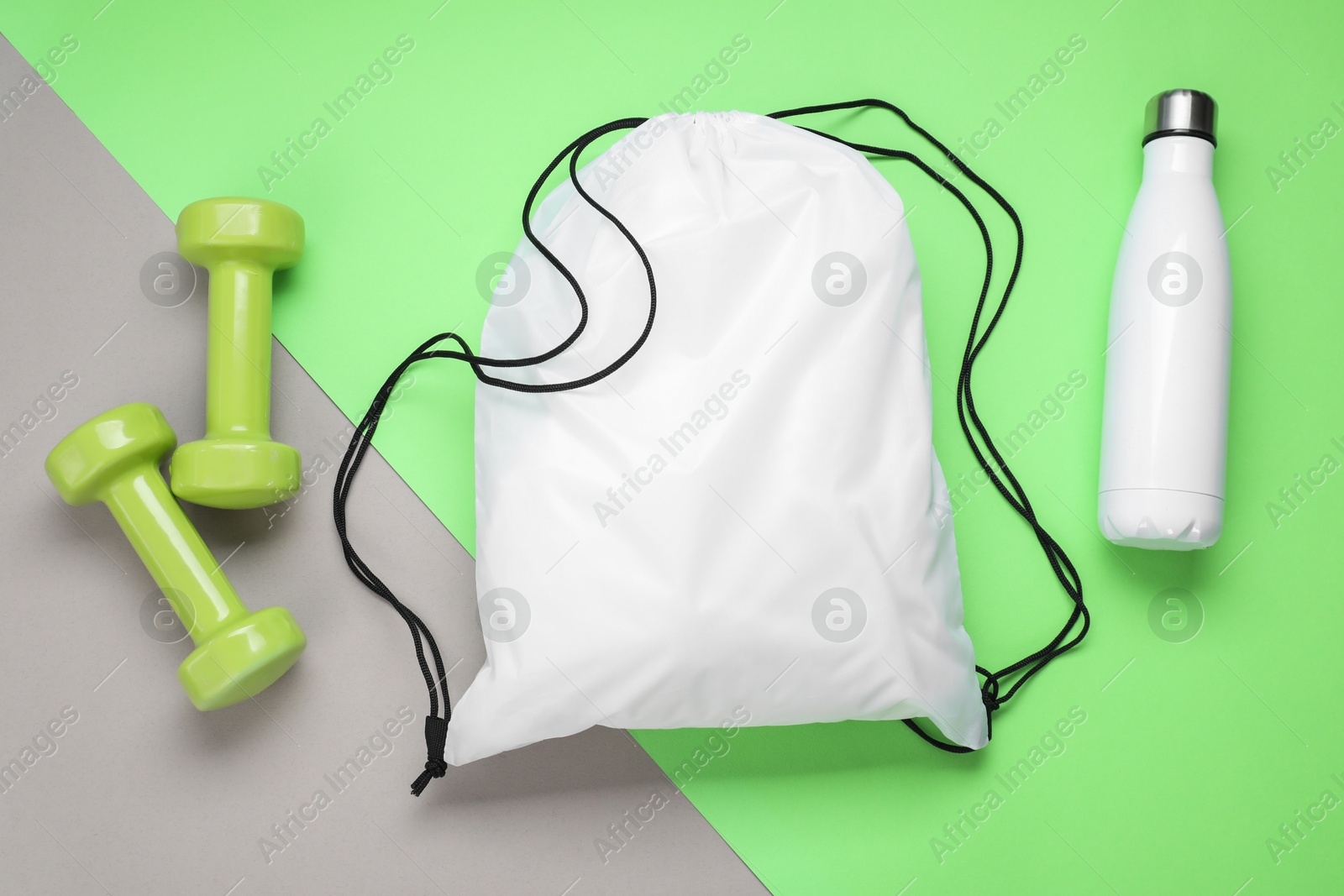 Photo of White drawstring bag, thermo bottle and dumbbells on color background, flat lay