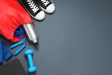 Photo of Red drawstring bag, sneakers and sports equipment on grey background, flat lay. Space for text