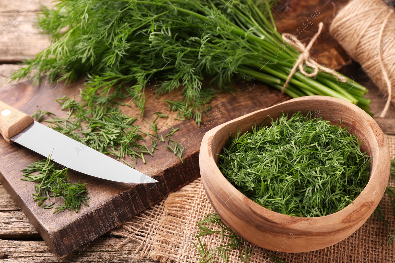 Photo of Fresh dill, cutting board and knife on wooden table