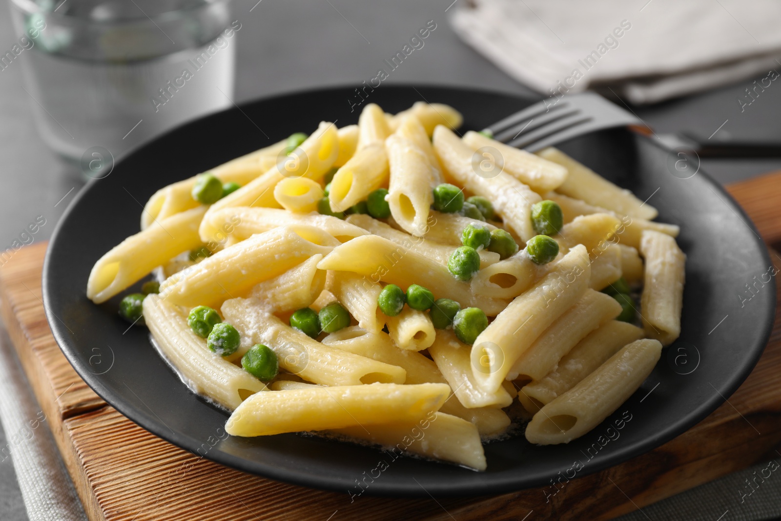 Photo of Delicious pasta with green peas, cheese and fork on table, closeup