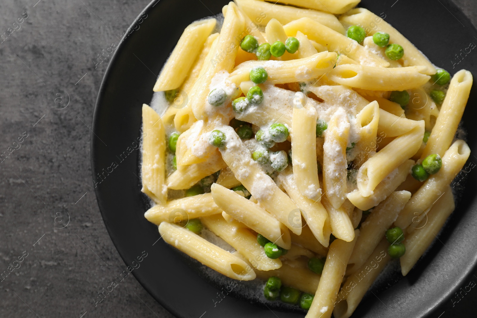 Photo of Delicious pasta with green peas and creamy sauce on grey table, top view