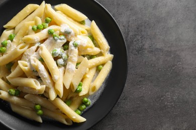 Photo of Delicious pasta with green peas and creamy sauce on grey table, top view. Space for text