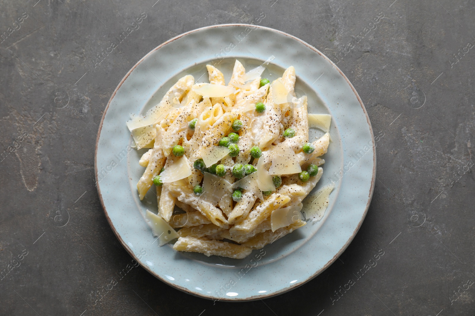 Photo of Delicious pasta with green peas, cheese and creamy sauce on grey table, top view