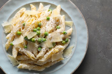 Photo of Delicious pasta with green peas, cheese and creamy sauce on grey table, top view