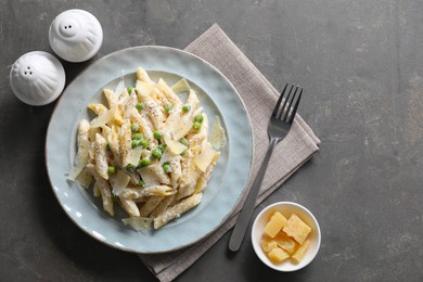 Delicious pasta with green peas, cheese and creamy sauce on grey table, top view