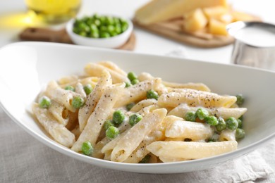 Photo of Delicious pasta with green peas and creamy sauce in bowl on table, closeup