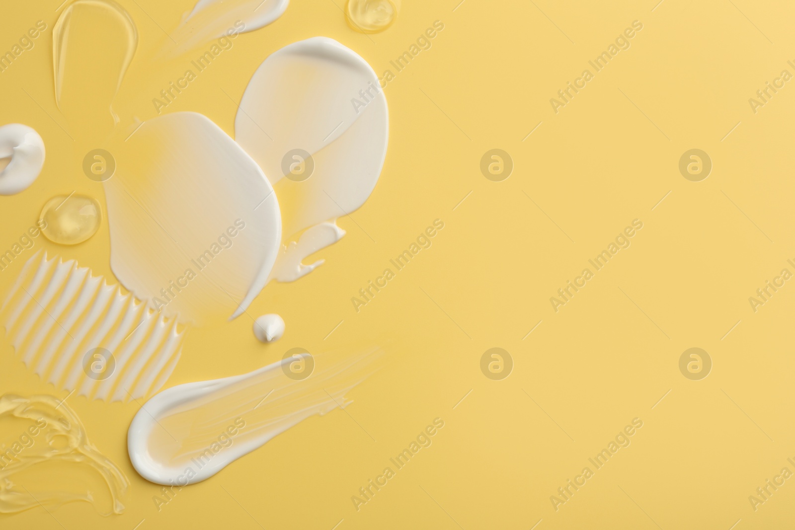 Photo of Samples of face cream on yellow background, top view. Space for text