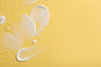 Photo of Samples of face cream on yellow background, top view. Space for text