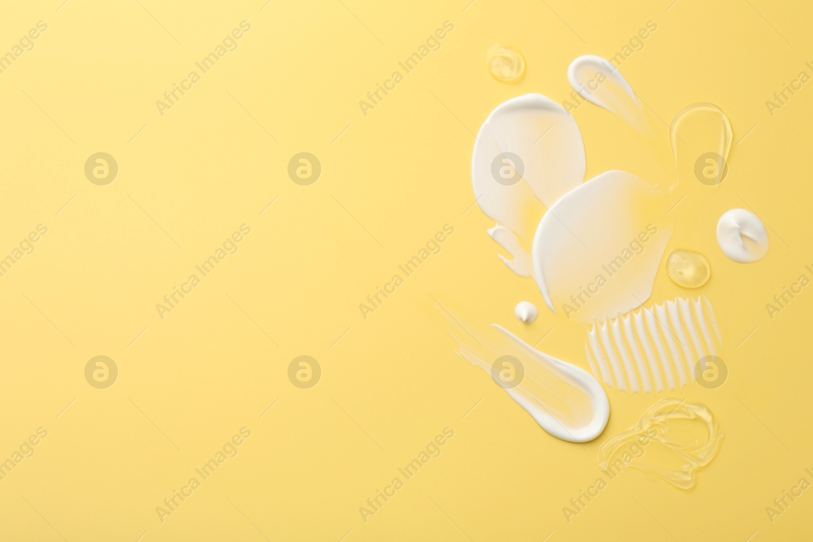 Photo of Samples of face cream on yellow background, top view. Space for text