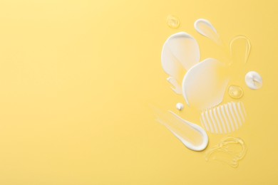 Photo of Samples of face cream on yellow background, top view. Space for text