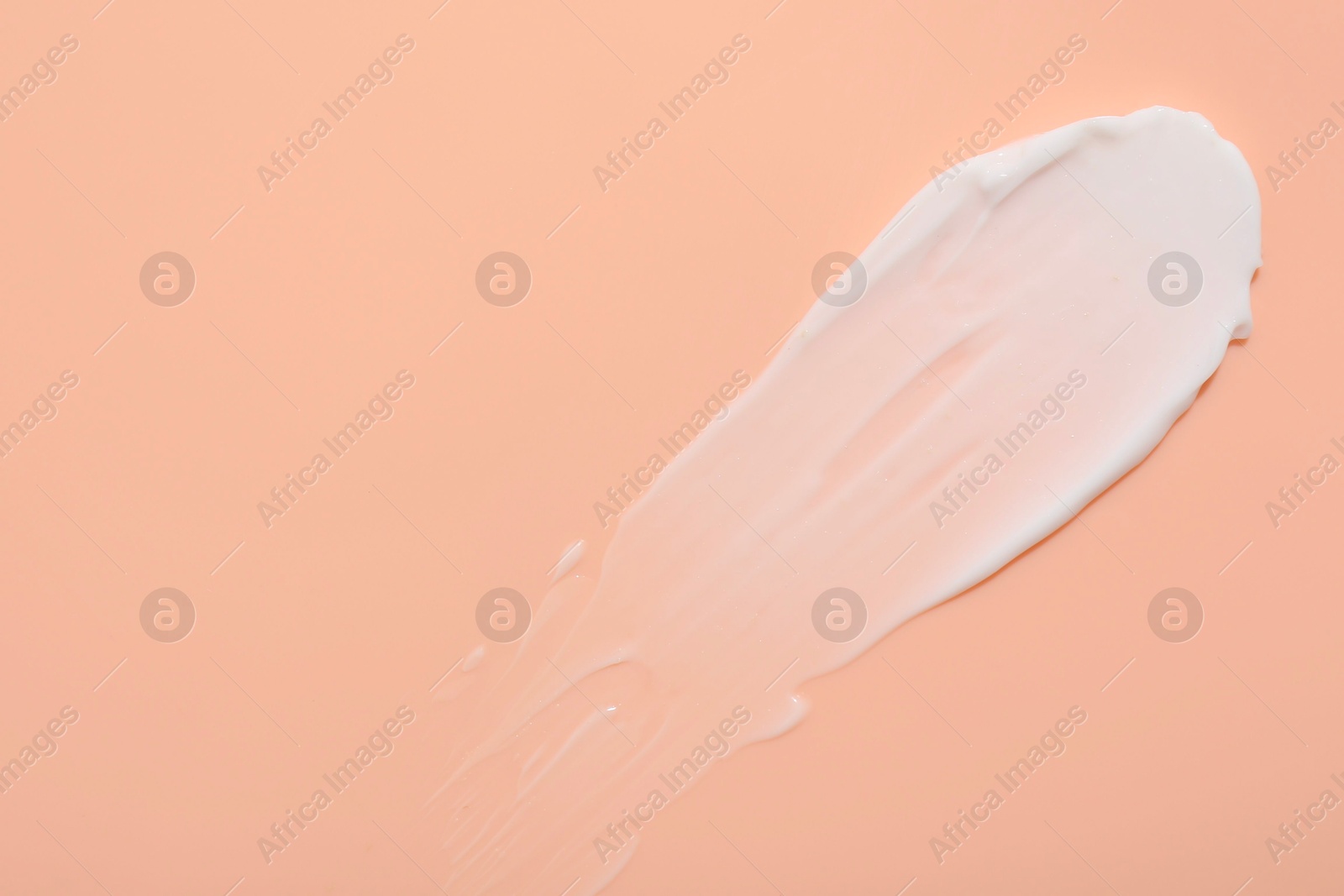 Photo of Sample of face cream on coral background, top view. Space for text