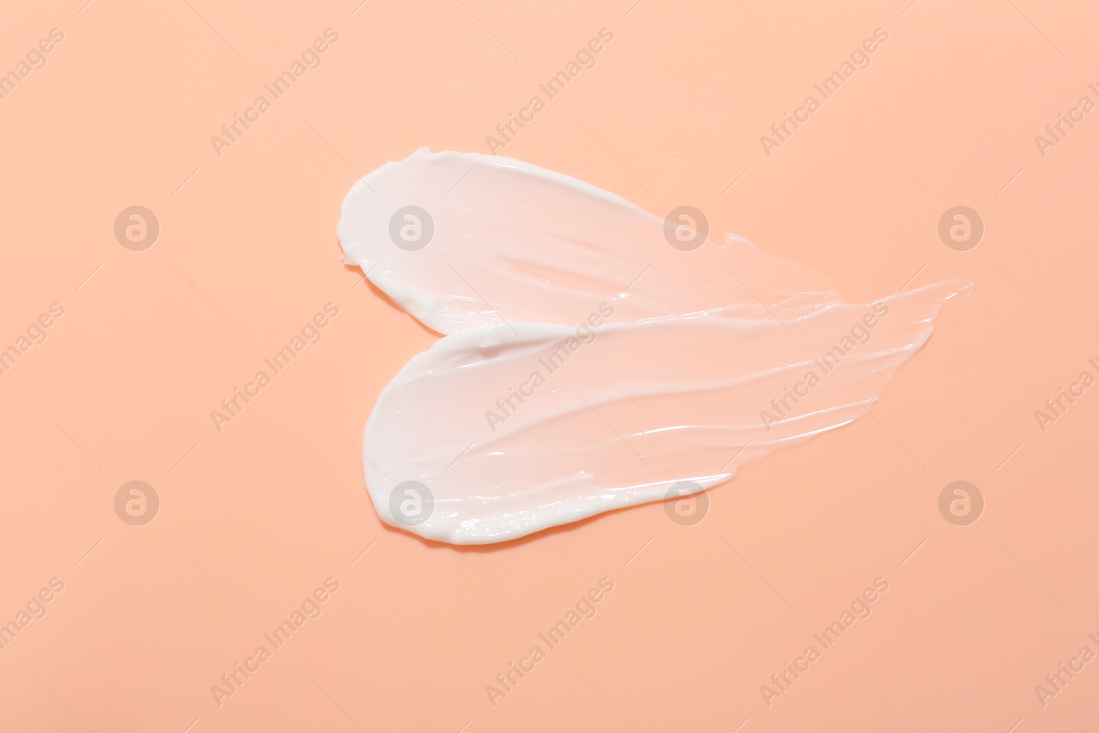 Photo of Samples of face cream on coral background, top view