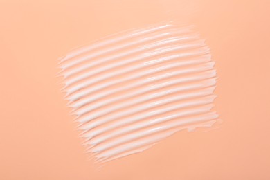 Face cream on coral background, top view