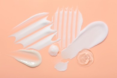 Photo of Samples of face cream on coral background, top view