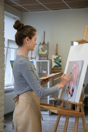 Photo of Woman drawing beautiful flamingo with brush in studio