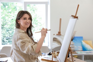 Photo of Smiling woman drawing picture with brush in studio