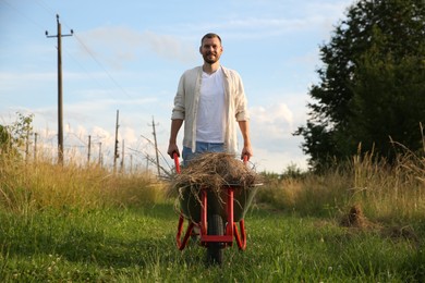 Photo of Farmer with wheelbarrow full of mown grass outdoors