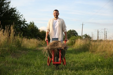 Farmer with wheelbarrow full of mown grass outdoors