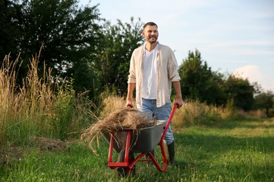 Farmer with wheelbarrow full of mown grass outdoors