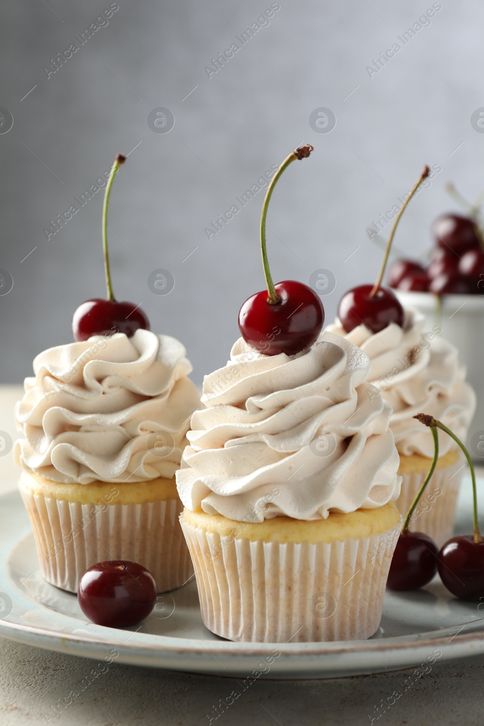 Photo of Delicious cupcakes with cream and cherries on light table, closeup