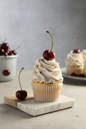 Photo of Delicious cupcake with cream and cherries on light textured table