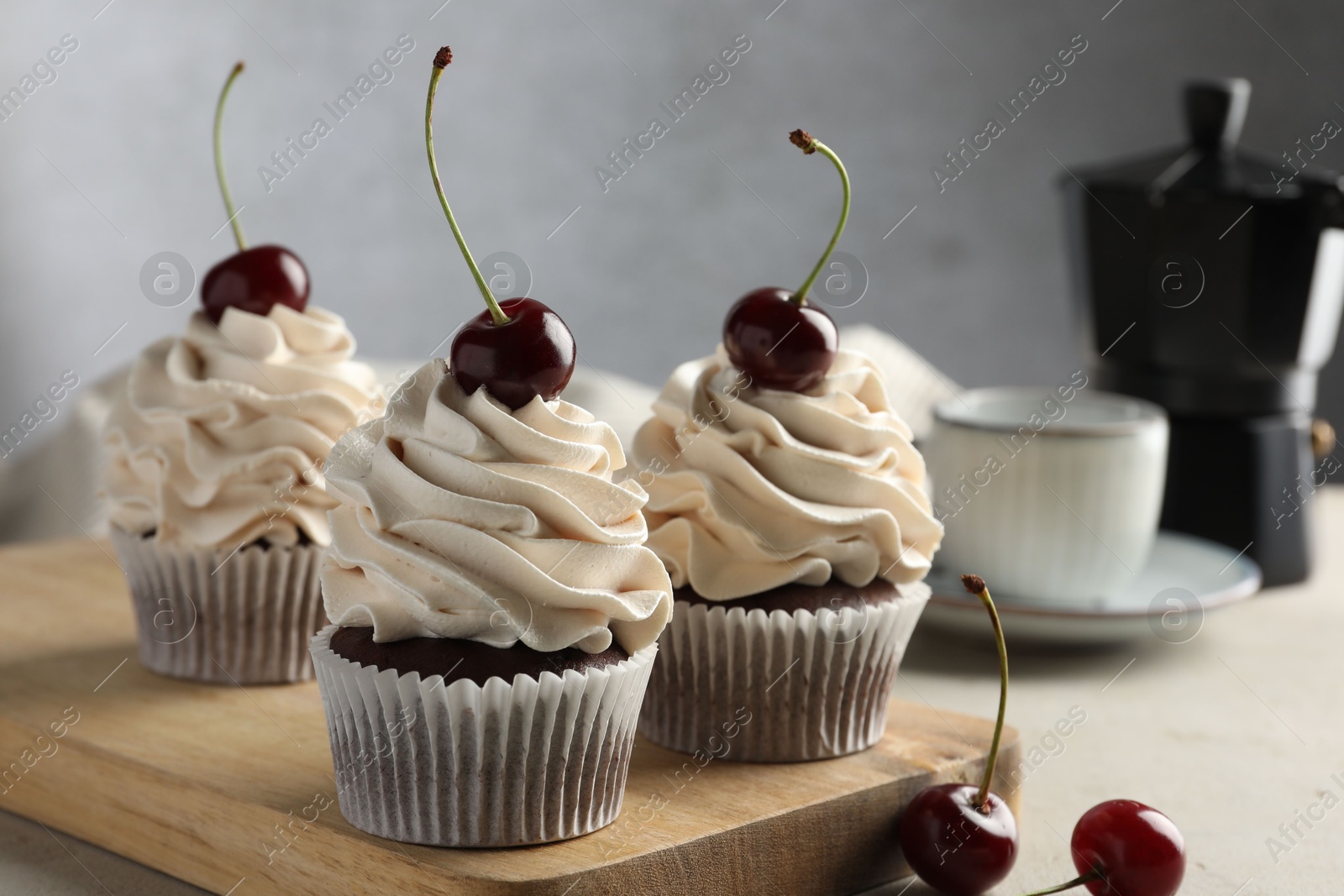 Photo of Delicious cupcakes with cream and cherries on light table, closeup