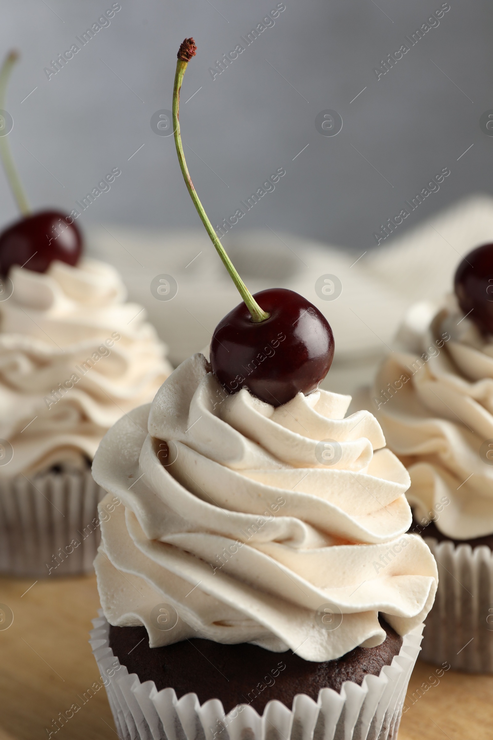 Photo of Delicious cupcakes with cream and cherries on table, closeup