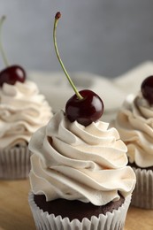 Photo of Delicious cupcakes with cream and cherries on table, closeup