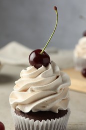 Delicious cupcake with cream and cherry on table, closeup