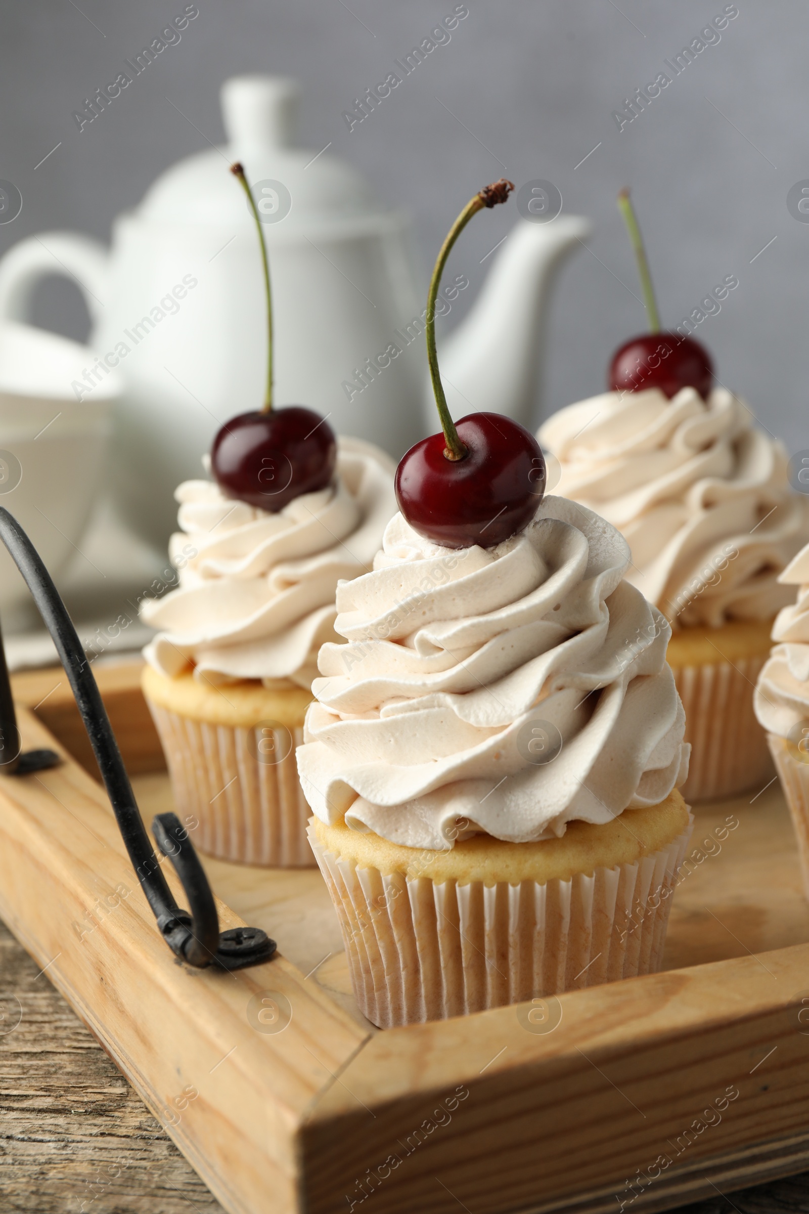 Photo of Delicious cupcakes with cream and cherries on wooden table, closeup