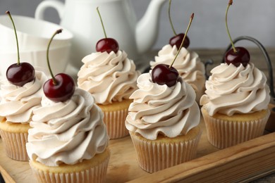 Photo of Delicious cupcakes with cream and cherries on table, closeup