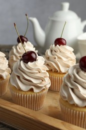 Delicious cupcakes with cream and cherries on table, closeup