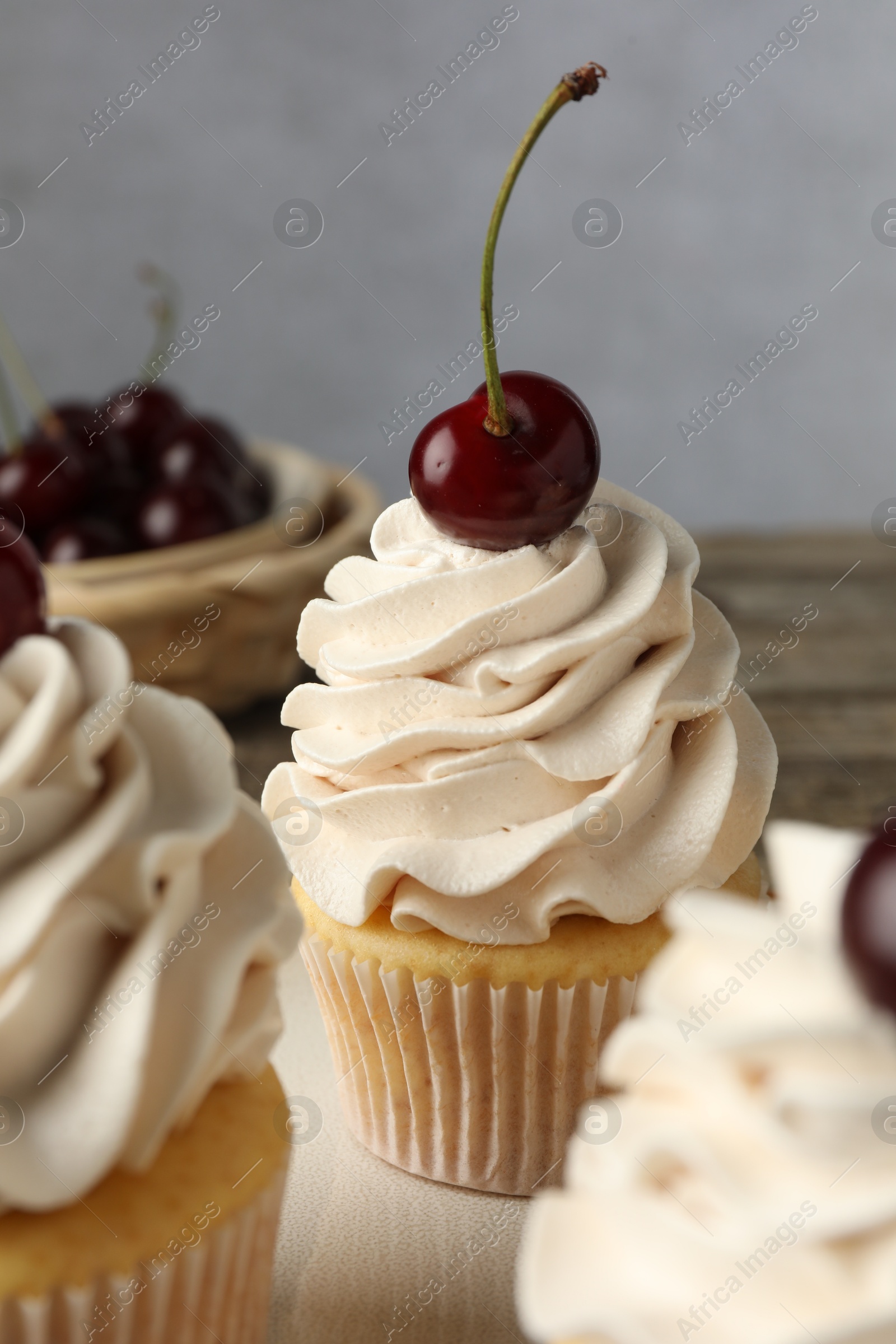 Photo of Delicious cupcakes with cream and cherries on table, closeup