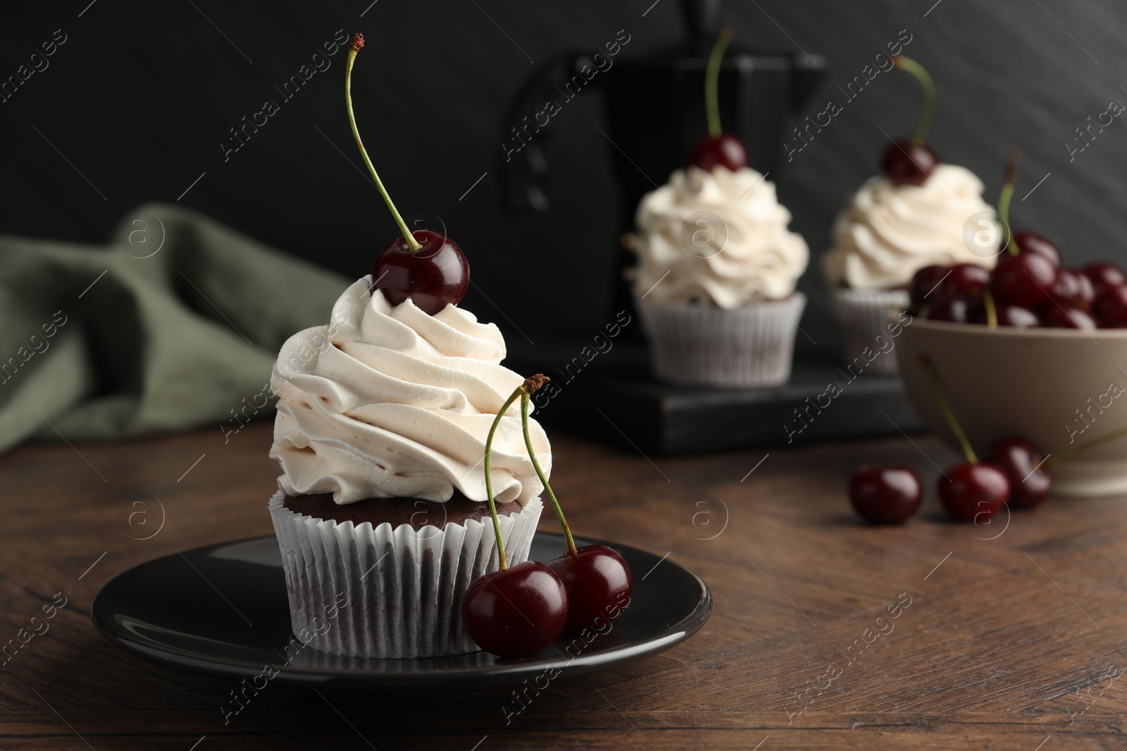 Photo of Delicious cupcakes with cream and cherries on wooden table, closeup